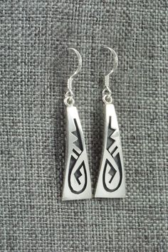 These sterling silver earrings were made by Hopi silversmith Augustine Mowa. The back is stamped sterling.Length: 1 1/2"Width: 3/8"Free shipping on all orders! We ship with USPS and always include tracking. All orders ship within a day of payment.Returns are accepted up to 30 days after you receive your order. Just send us a message. Our shop offers cash back or store credit. The item must be returned in new condition. Engraved Teardrop Sterling Silver Earrings, Engraved Sterling Silver Dangle Earrings, Symbolic Hallmarked Sterling Silver Earrings, Southwestern Sterling Silver Beaded Earrings, Southwestern Style Sterling Silver Drop Earrings, Silver Southwestern Drop Earrings, Southwestern Hand-strung Sterling Silver Jewelry, Turquoise Southwestern Nickel-free Hoop Earrings, Native American Jewelry