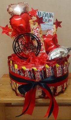 a basket filled with candy and wrapped in red ribbon on top of a wooden table