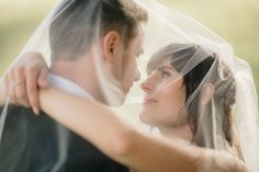 a bride and groom embracing under a veil