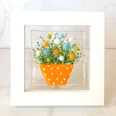 an orange and white vase with flowers in it