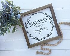 a wooden frame with a quote on it next to some beads and a potted plant