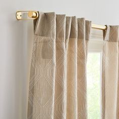 a curtain with gold hardware hanging from it's side in front of a window