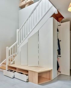 an open closet under the stairs in a house with white walls and wooden steps leading up to it's second floor