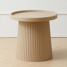 a round table sitting on top of a hard wood floor next to a white wall