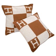 two brown and white checkered pillows with the letter h on it's sides