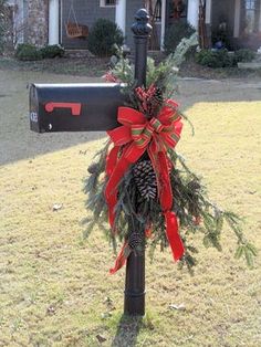 a mailbox decorated with red bows and pine cones is in front of a house