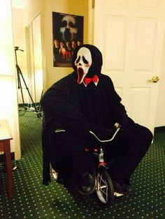 a man in a costume riding a bike with a creepy face on it's head