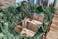 two stainless steel sinks sitting on top of a green marble countertop in a kitchen