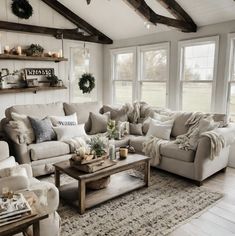 a living room filled with lots of furniture next to two windows and a rug on the floor