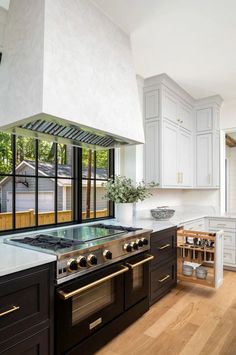 a kitchen with an oven, stove and cabinets in the middle of it is surrounded by wood flooring