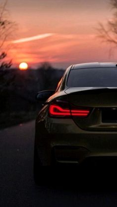 the back end of a car on a road at sunset