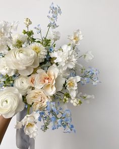 a bouquet of white and blue flowers in someone's hand on a white background