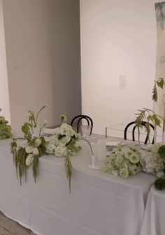 the table is set up with white flowers and greenery for an elegant wedding reception