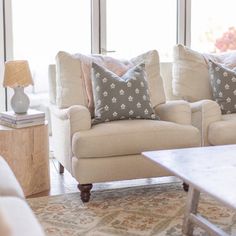 a living room with two couches and a coffee table in front of large windows