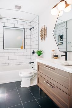 a bathroom with black and white tile flooring and wooden cabinetry, along with a large mirror above the toilet