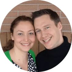 a man and woman are smiling in front of a brick wall with a circle frame