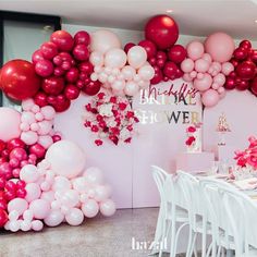 a room filled with lots of pink and white balloons