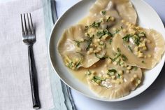 a white plate topped with dumplings covered in gravy next to a fork