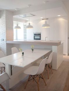 a white kitchen with an island table and chairs