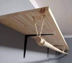 a piece of wood is hanging from the ceiling with ropes attached to it and two wooden pegs on each end