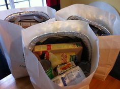 two white paper bags filled with food sitting on top of a wooden table next to a window