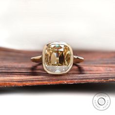 a fancy yellow diamond ring sitting on top of a wooden table