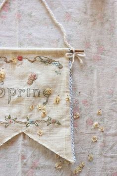 an embroidered banner hanging on a wall with flowers and words written in it that say spring