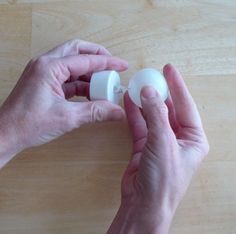 two hands holding an object on a wooden surface