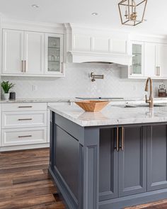 a large kitchen with white cabinets and marble counter tops, an island in the middle