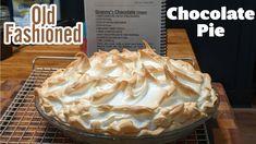 an old fashioned chocolate pie sitting on top of a cooling rack next to a recipe book