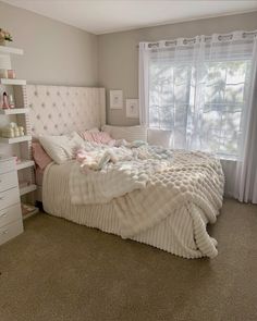 a white bed in a bedroom next to a window