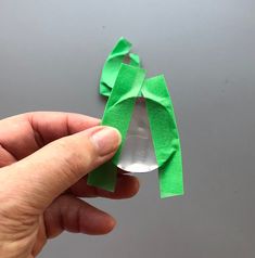 a person holding a piece of green paper with a bow on it's side