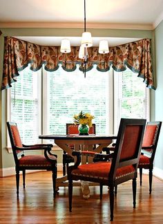 a dinning room table with four chairs in front of a window and two windows