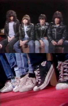 the group of young men are sitting on a red carpet and wearing black leather jackets