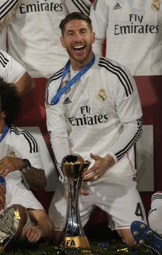 the soccer player smiles as he holds his trophy