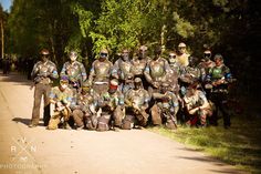 a group of people in paintball suits posing for a photo on the side of a road