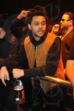 a man standing in front of a group of people holding onto bottles and looking at the camera