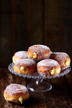 powdered sugar covered donuts on a glass plate