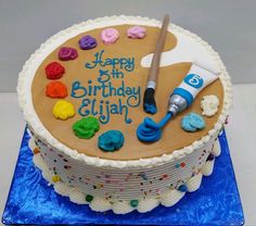 a birthday cake decorated with icing and paintbrushes