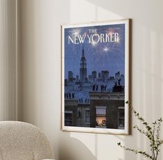 a framed poster hangs on the wall next to a chair and vase filled with flowers