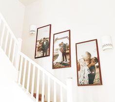 three framed photos hang on the wall next to a stair case in a white room