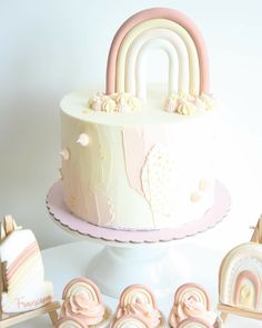 a white cake with pink frosting and rainbow decorations on top, surrounded by small wooden toys