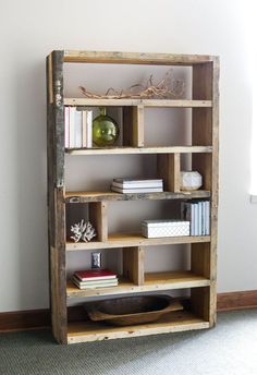 an old wooden book shelf with books and other items on it, against a white wall