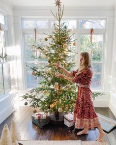 a woman decorating a christmas tree in her living room