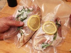 a person holding two lemon slices in plastic bags on a wooden table next to an apple