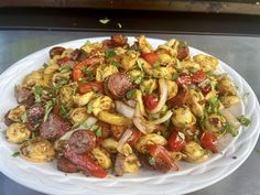 a white plate topped with lots of food on top of a metal table next to a window