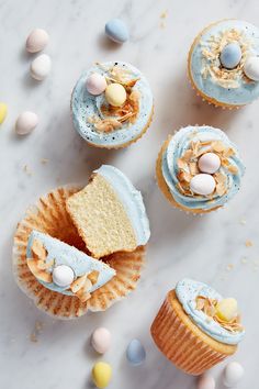 cupcakes with blue frosting and candies on them sitting on a marble surface