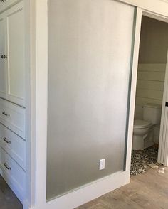 an empty bathroom with white cabinets and wood flooring in the middle of the room