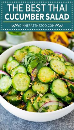 a white bowl filled with cucumbers and onions next to other vegetables on a table