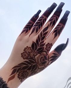 a woman's hand with black and brown henna tattoos on her left arm